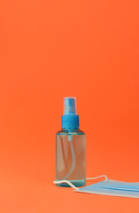Hygienic and health measures. Hand sanitizer gel and surgical mask on orange background.