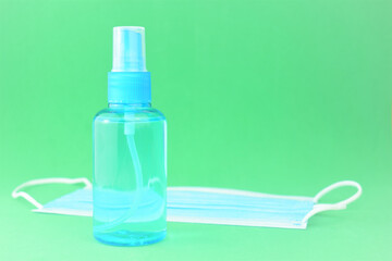 Hygienic and health measures. Hand sanitizer gel and surgical mask on green background.