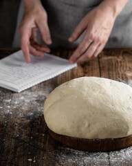 man looking recipe in a notebook and prepares dough in the kitchen 