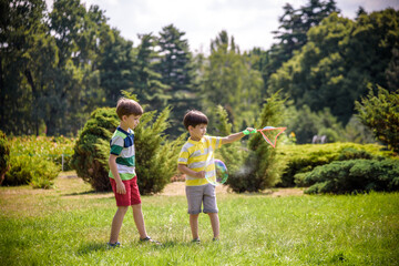 Fototapeta premium Boy blowing soap bubbles while an excited kid enjoys the bubbles. Happy teenage boy and his brother in a park enjoying making soap bubbles. Happy childhood friendship concept