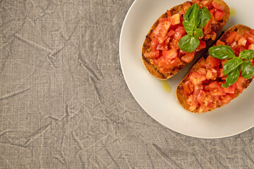 Bruschetta (toasted bread) with tomato and basil on the plate. Classic Italian appetizer.  Flat lay. Copy space.