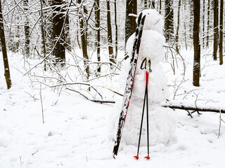 handcrafted snowman with skis in snowy city park on overcast winter day