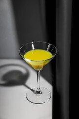 Orange juice or lemon alcohol cocktail in glass on the marble table. Yellow and grey trendy colors of 2021 years still life