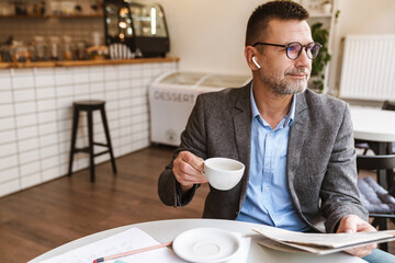 Handsome businessman reading newspaper in cafe