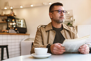 Handsome confident businessman reading newspaper