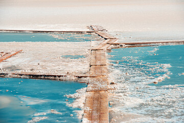 Closeup of salt layers on the shores of a pink salt lake. Old wooden way. Pedestrian wooden footbridge.
