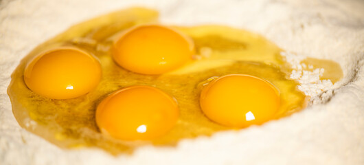 (Selective focus) Close-up view of a heap of flour with some fresh eggs inside. Flat lay, Ingredients for a homemade dough such as pasta, bakery, cakes etc.