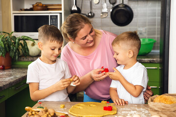 Caring mother help little preschooler sons prepare cookies, smiling loving mom learn cooking with small boys child, making lunch on weekend in kitchen together