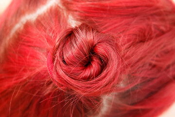 Bright dyed ruby red hair gathered in a bun up close.