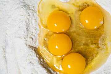 (Selective focus) Close-up view of a heap of flour with some fresh eggs inside. Flat lay, Ingredients for a homemade dough such as pasta, bakery, cakes etc.