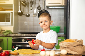 Indoor activity. Young positive child boy cooking in the kitchen. Make cookies