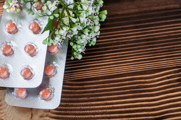 Fresh (Valeriana officinalis) flowers and Pills valerian on wooden background. Used as an alternative to valium in natural medicine, Close up. Flat lay. Copy space.