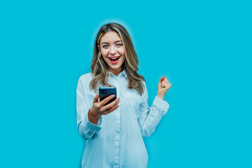 Attractive girl on a blue background with a phone in her hands, she is happy with the purchase she made online. Place for text, online shopping