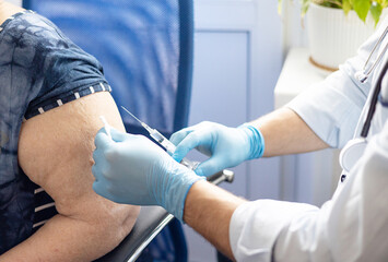 young doctor making a vaccination to the elderly woman