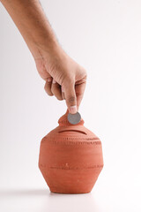 Obraz na płótnie Canvas putting a coin into a clay money box: investments, retirement fund and banking concept