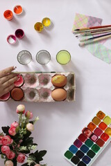 painting eggs for Easter, eggs, paints, brushes lie on a pink background