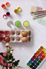 painting eggs for Easter, eggs, paints, brushes lie on a pink background