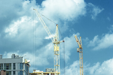 Yellow tower crane build house by blue cloudy sky background