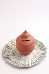 Clay piggy bank pot with five hundred rupees bank note in indian currency on white background