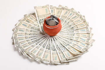 Clay piggy bank pot with five hundred indian rupees bank note on white background