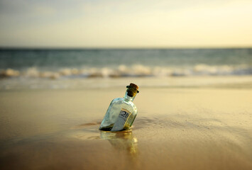 Obraz premium Bottle with twenty pound note inside found in the sand of beach