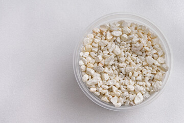 Top view of a plastic jar with decorative stones on a white background