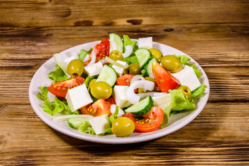Ceramic plate with greek salad on wooden table