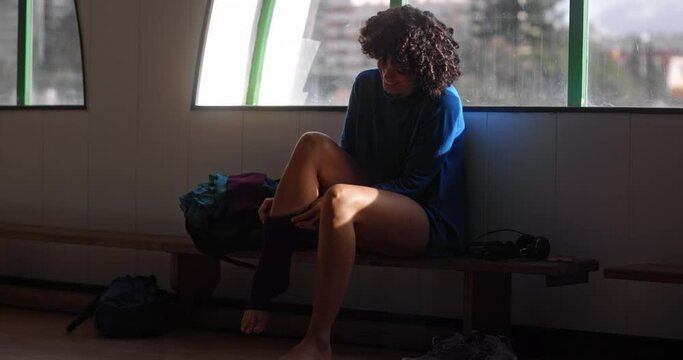 African-american woman with afro hair dressing socks on dance studio
