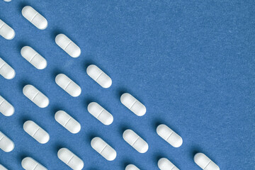 Blue medicine background with white pills and tablet, macro. Drug production.