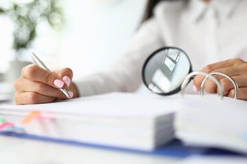 Female hands holding magnifying glass over folder with documents concept. Working in archive concept