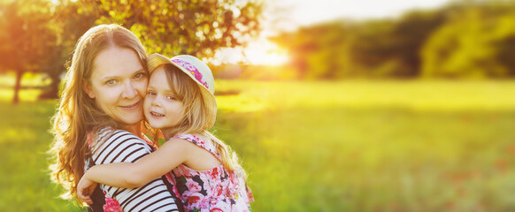 Pretty smiling girl and mother relaxing outdoor - panorama