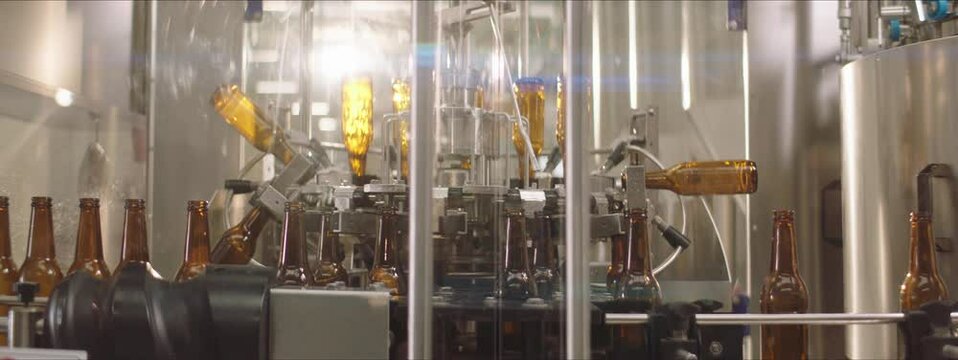 Video of bottles being washed on a modern bottle washing machine. Splashes of water. Manufacturing process. Factory concept.