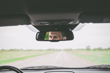 Reflection in the driver's gaze in the rear-view mirror of a car in motion