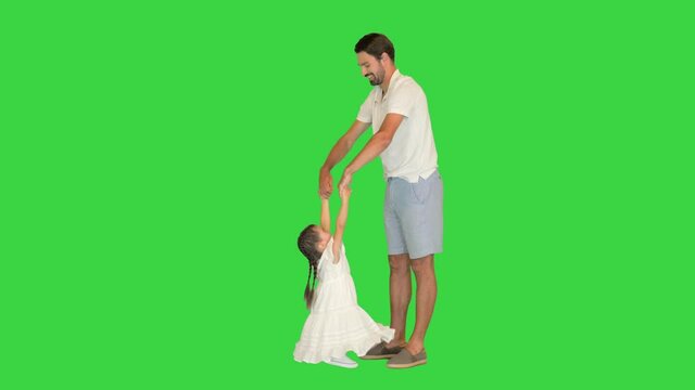 Happy dad is lifting up his little daughter on a Green Screen, Chroma Key.