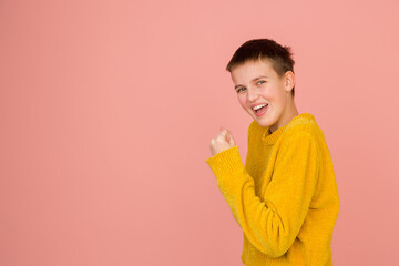 I can do it, winner. Caucasian girl's portrait on coral pink studio background with copyspace for ad. Beautiful model in sweater. Concept of human emotions, facial expression, sales, ad, fashion.