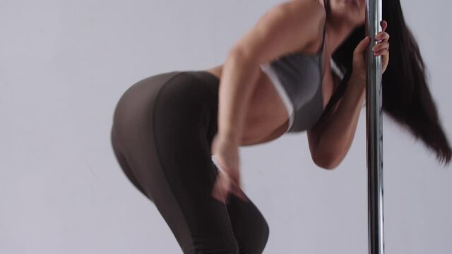 Pole dancing - a woman showing a basic movements by the pole