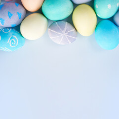Colorful Easter decorated eggs on bright blue table background.