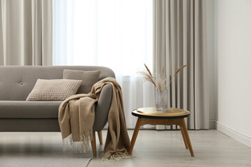 Grey sofa with pillows near window in stylish living room interior