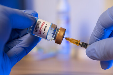 Doctor or Nurse holding syringe and COVID-19 vaccine. Healthcare And Medical concept.