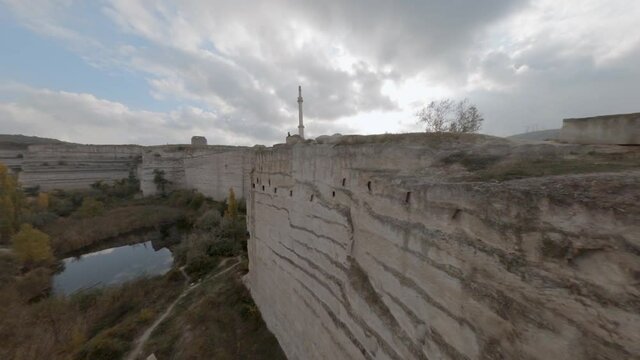 Aerial footage from sports fpv drone ancient stone fortress on mountain peak. Fpv sport drone flying through ruined tower ancient fortress in rocky cliff terrain 4k.