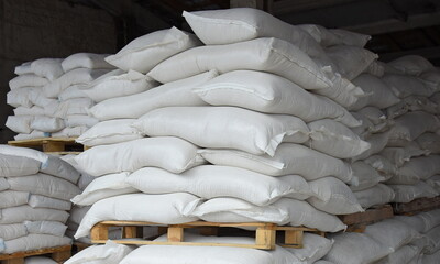 Bags of flour and grain in the warehouse are stacked on pallets, the factory is processing and...