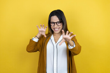 Young beautiful woman wearing a blazer over isolated yellow background smiling funny doing claw...