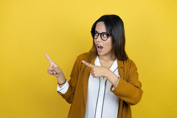 Young beautiful woman wearing a blazer over isolated yellow background pointing to the side with fingers