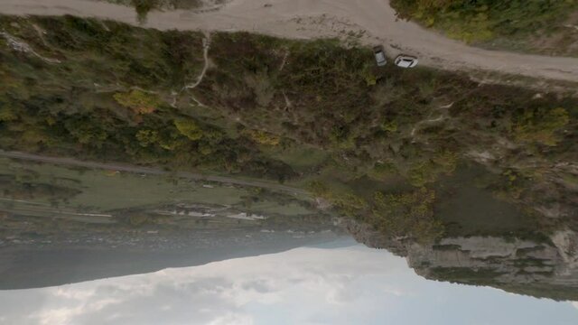 Sport fpv drone flying along white cliff. Copter flying through natural narrow tunnel in rocky fortress make power loop.