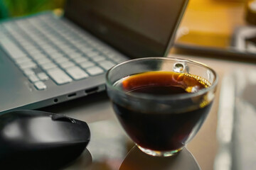 A cup of a coffee/tea and a laptop on fresh workplace desk. Surrounded by nature environment