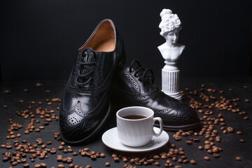 men's Italian boots on a black background with a cup of hot coffee. Ground roasted coffee beans