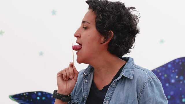 female speech therapist performing tongue exercise pressing tongue against wooden applicator stick