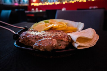 New York steak with a side of fried potatoes and a fajita, served in a Tex Mex restaurant