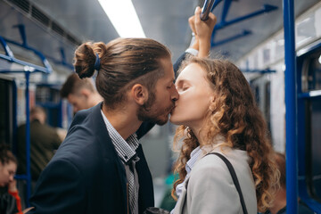 man and a woman in love kiss on a subway train.