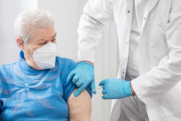 a doctor or nurse gives a senior a shot, perhaps a vaccination